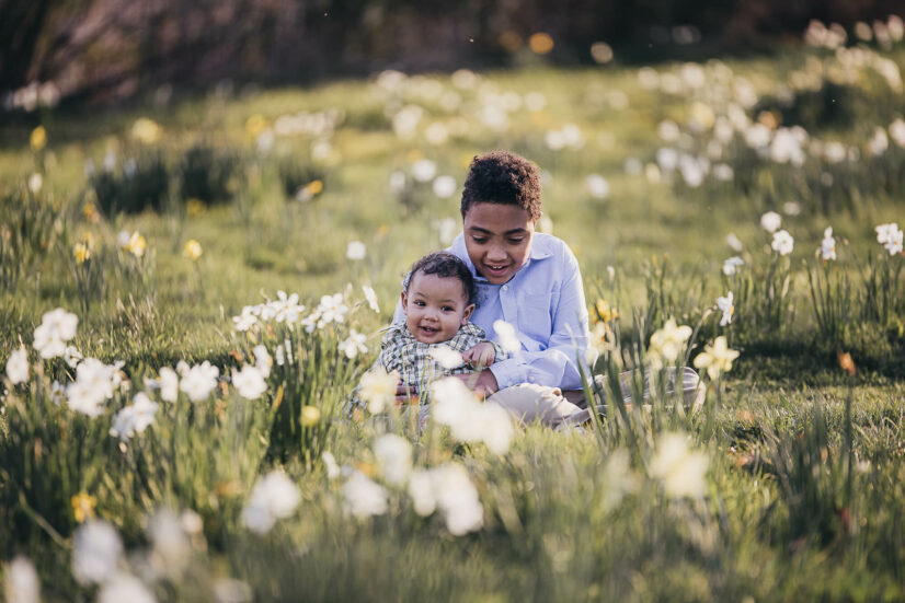 Older brother sitting with his sibling in a field of flowers Cleveland Clinic Pediatrics 