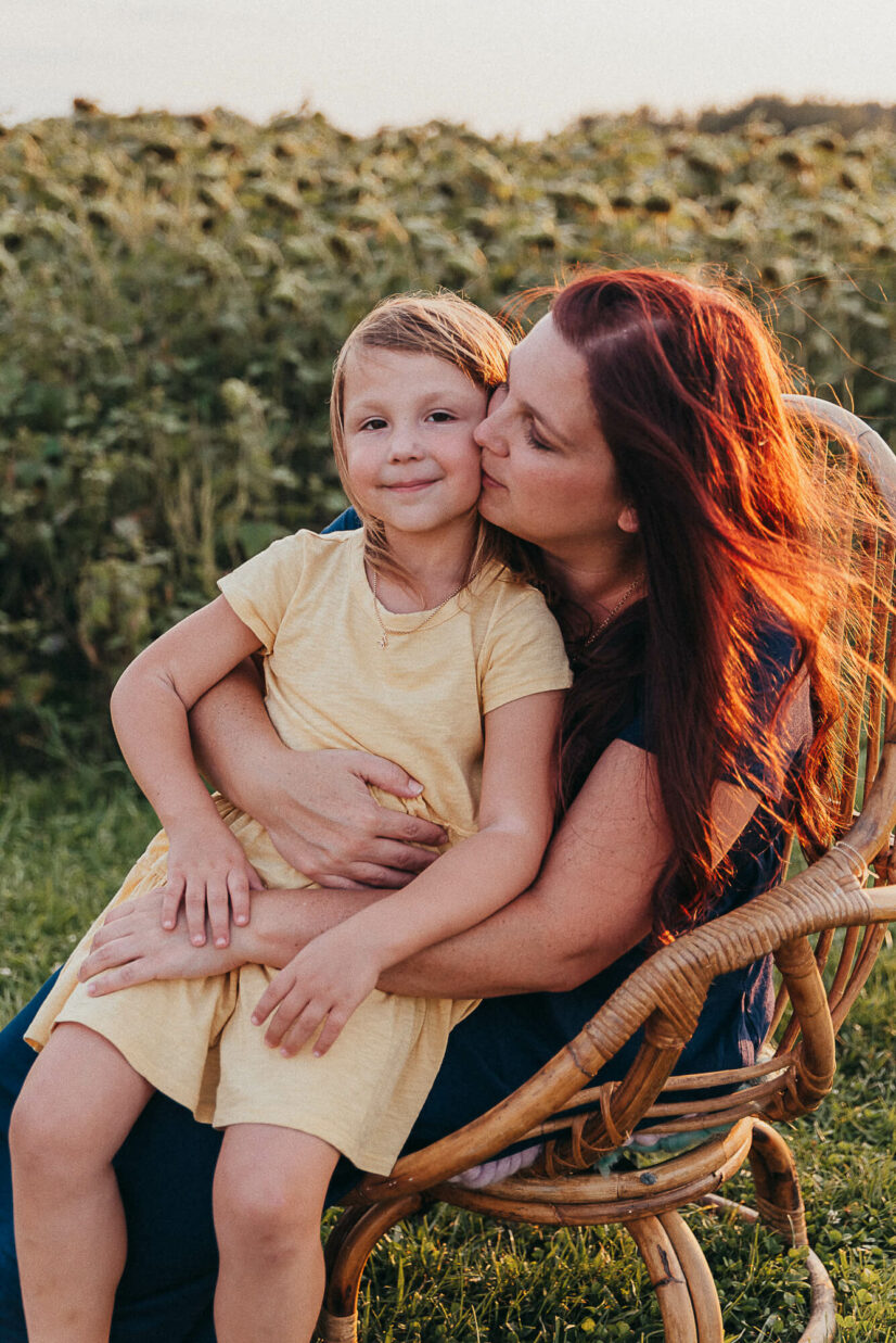 mom sitting in a wicker chair with her daughter on her lap 