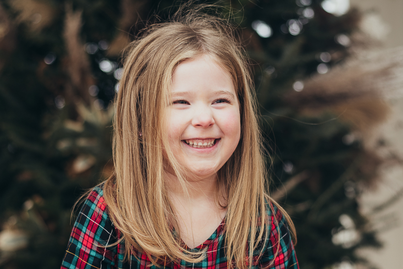 girl smiling in from of christmas tree kids kirthday parties cleveland family photographer
