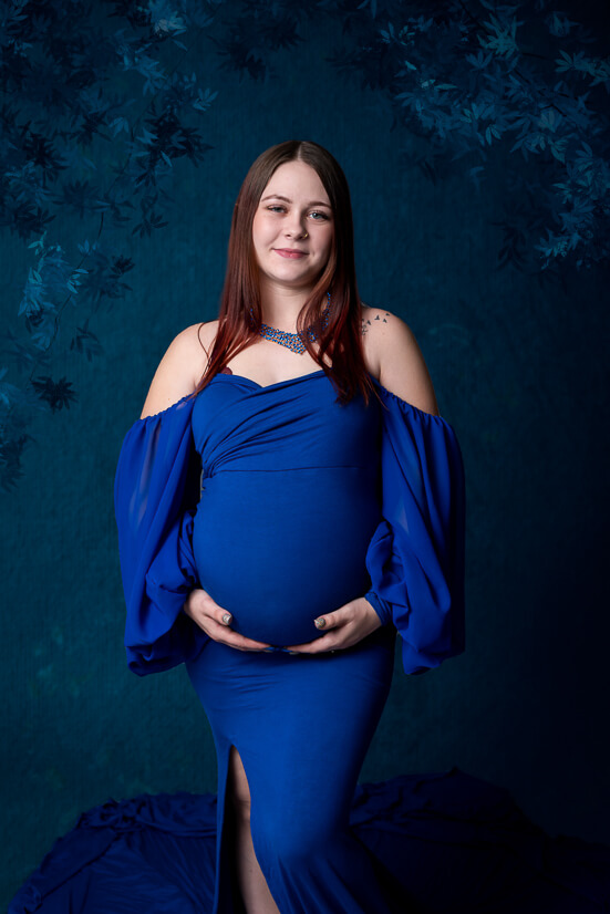 Mom looking at camera in blue dress for maternity the womb wellness center