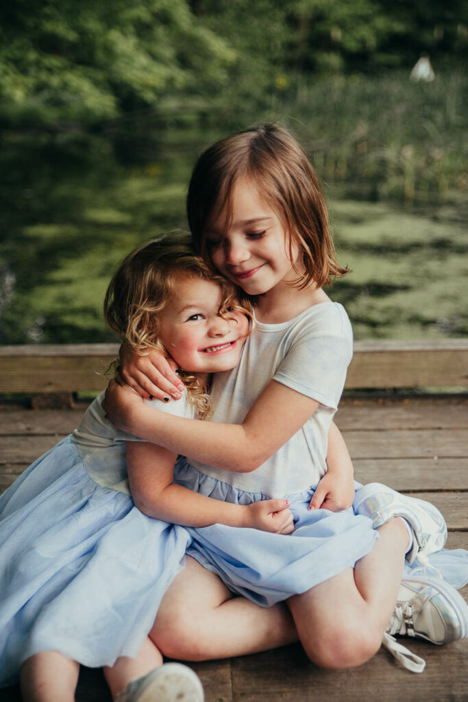 Two sisters hugging each other in a park during photography session for Things to do in Akron with kids