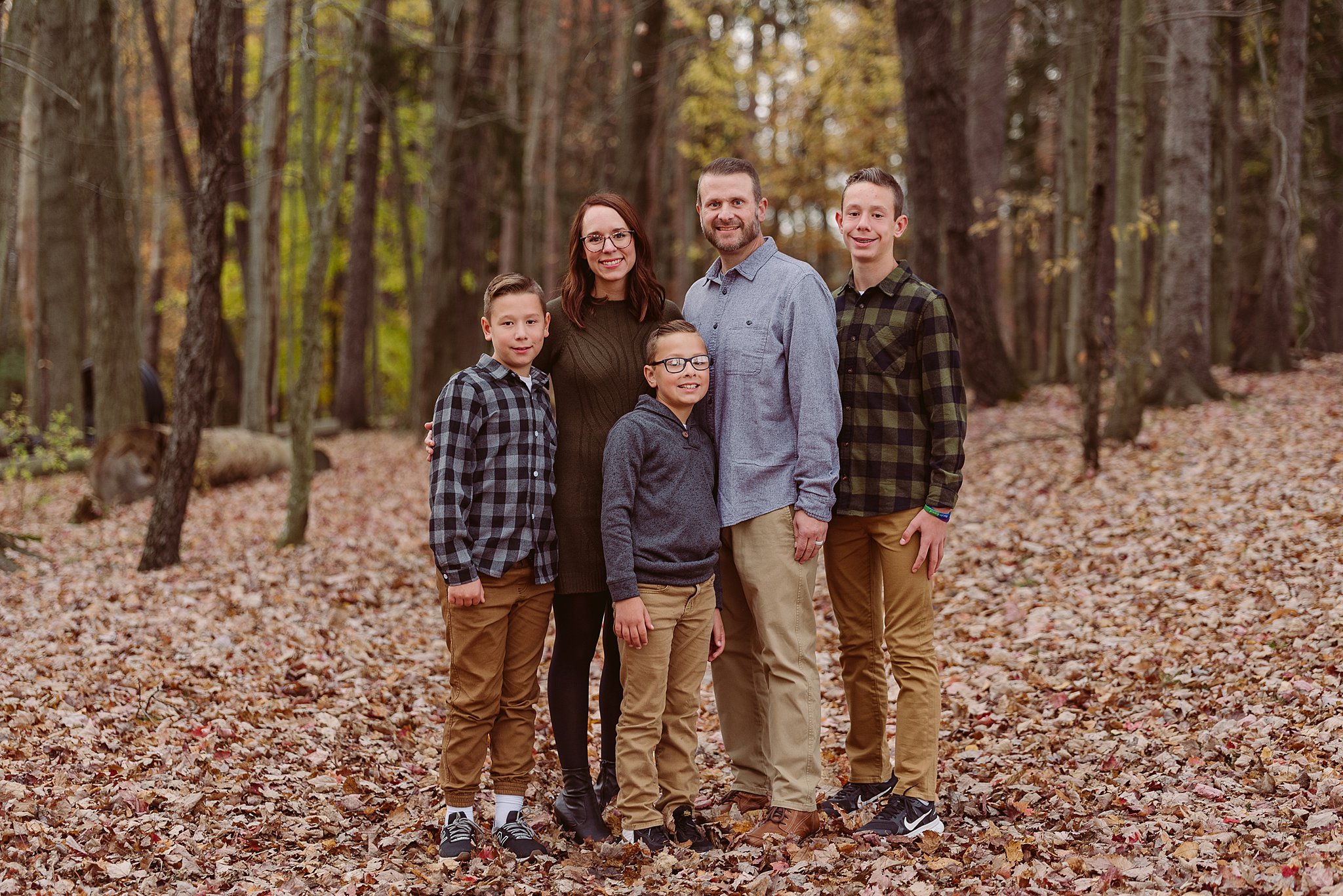 A family of five stand in the woods wearing khaki and flannel old navy mentor