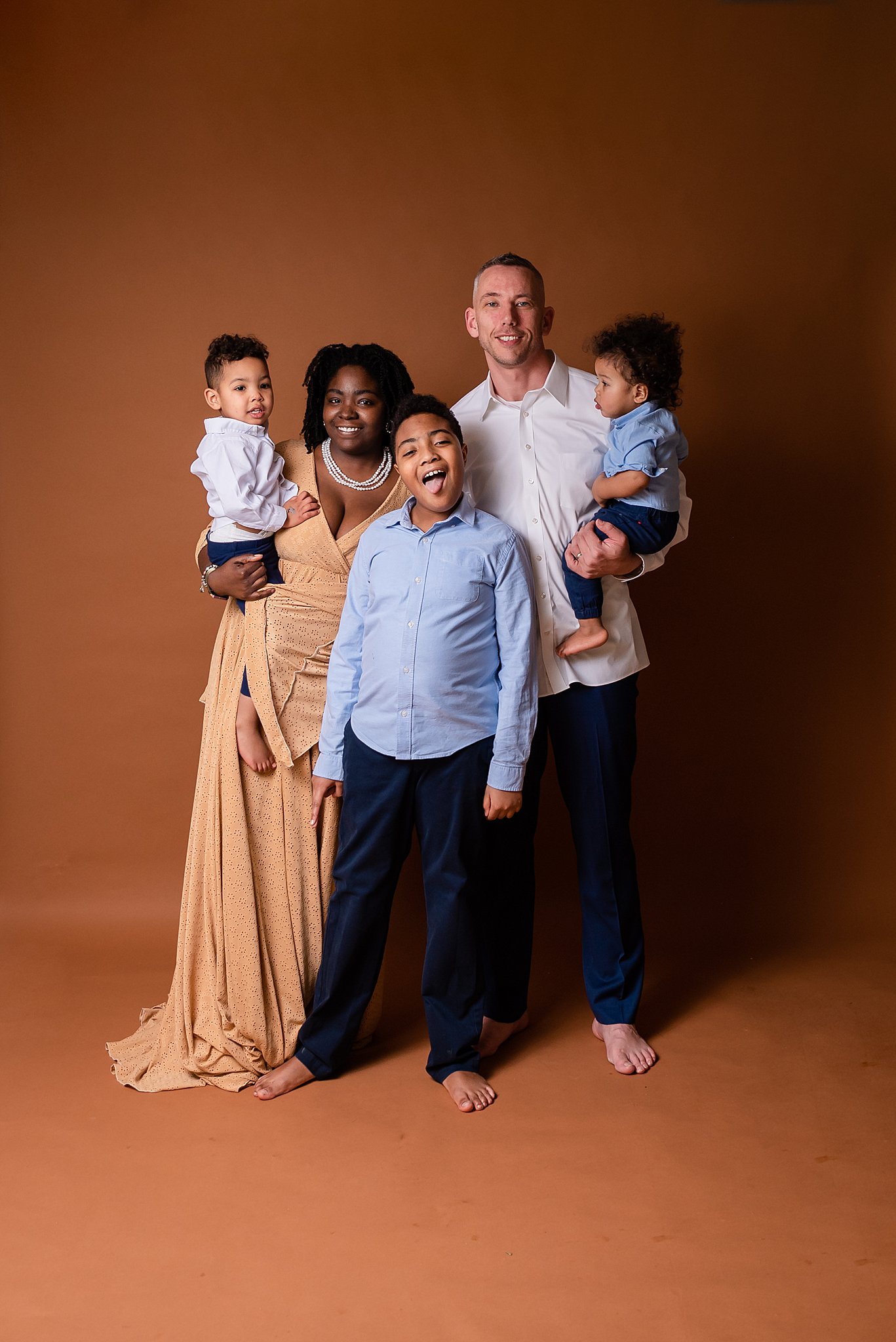 A family of five stands in a studio making faces playmatters toys