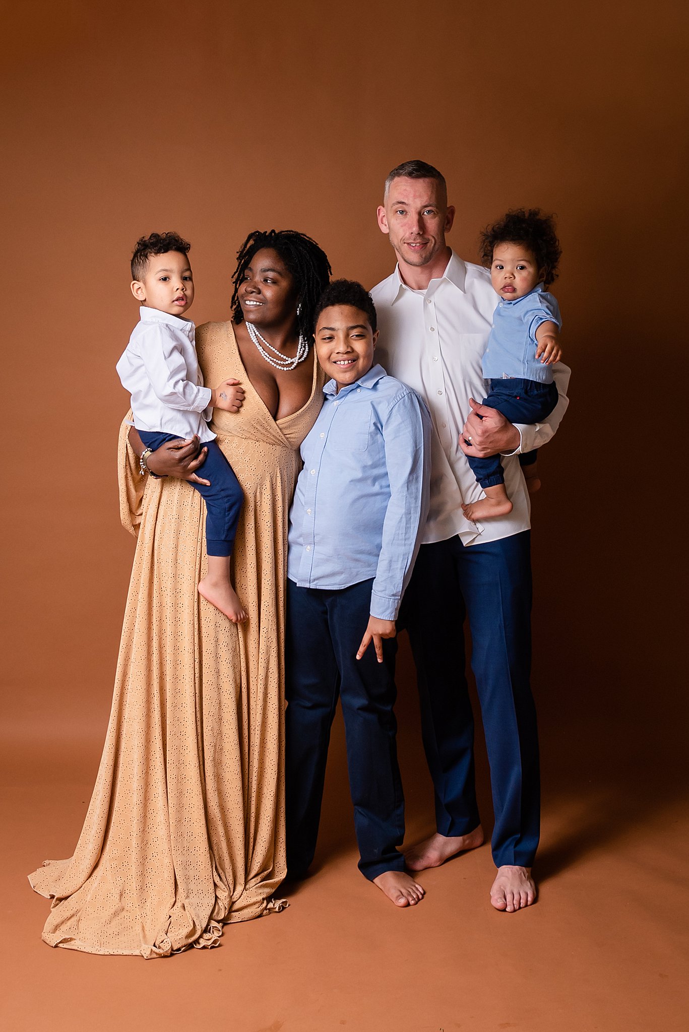 A family of five stands together in a studio with each parent holding a toddler on their hips recess cleveland