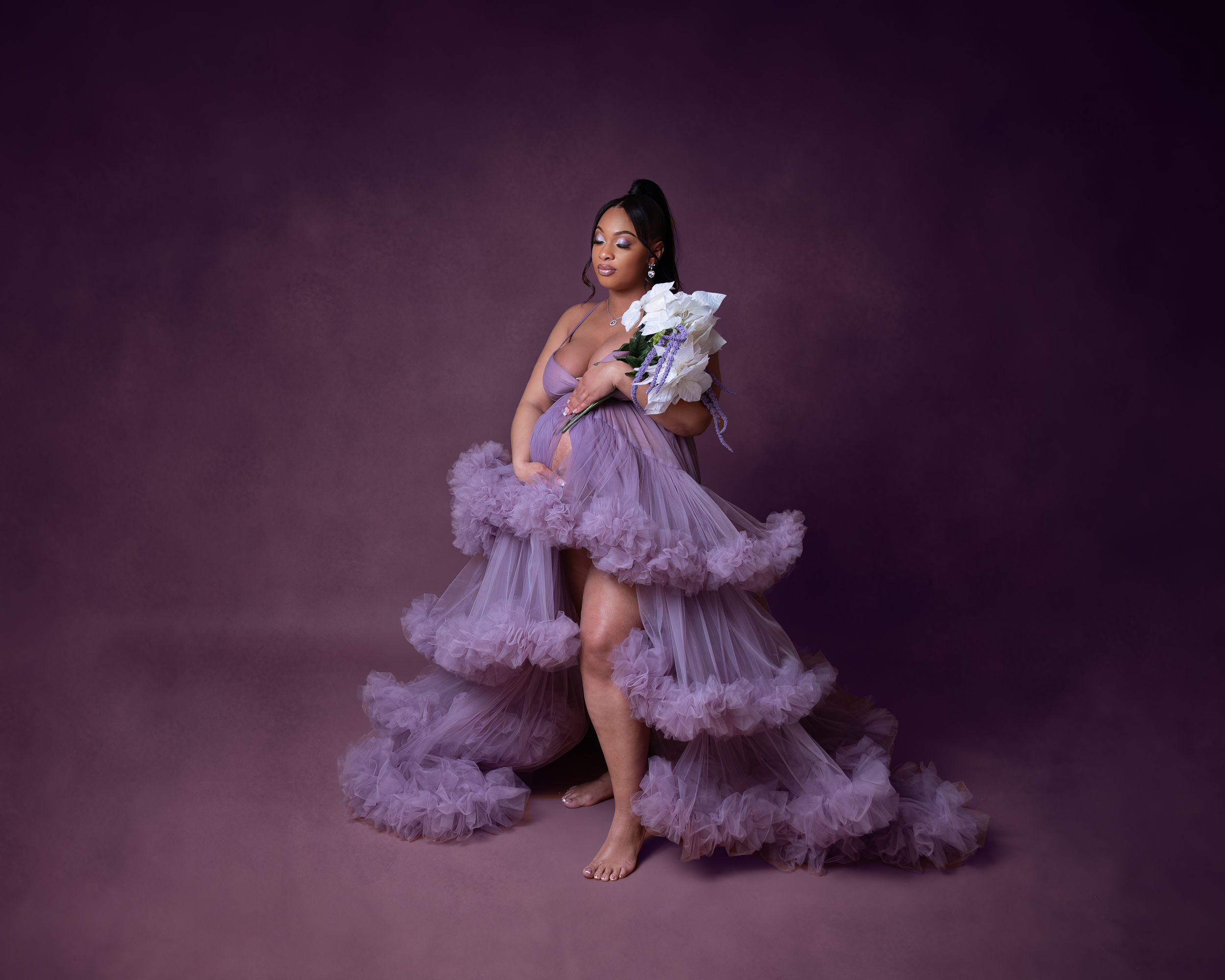 mother holding flowers in a purple fluffy dress with eyes closed cleveland maternity photographer