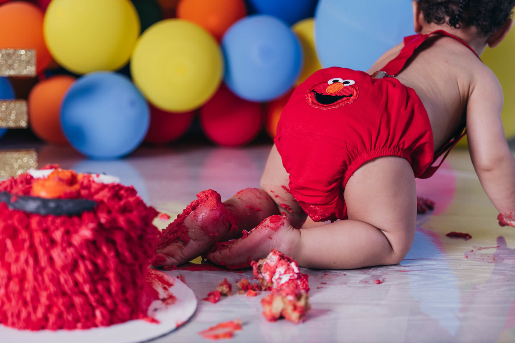 child with icing on foot from red elmo cake smash lakewood park