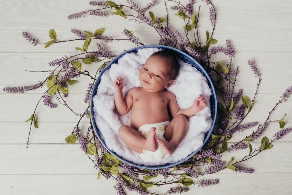 Newborn looking up at camera in a flower bowl for Cherub’s Blanket