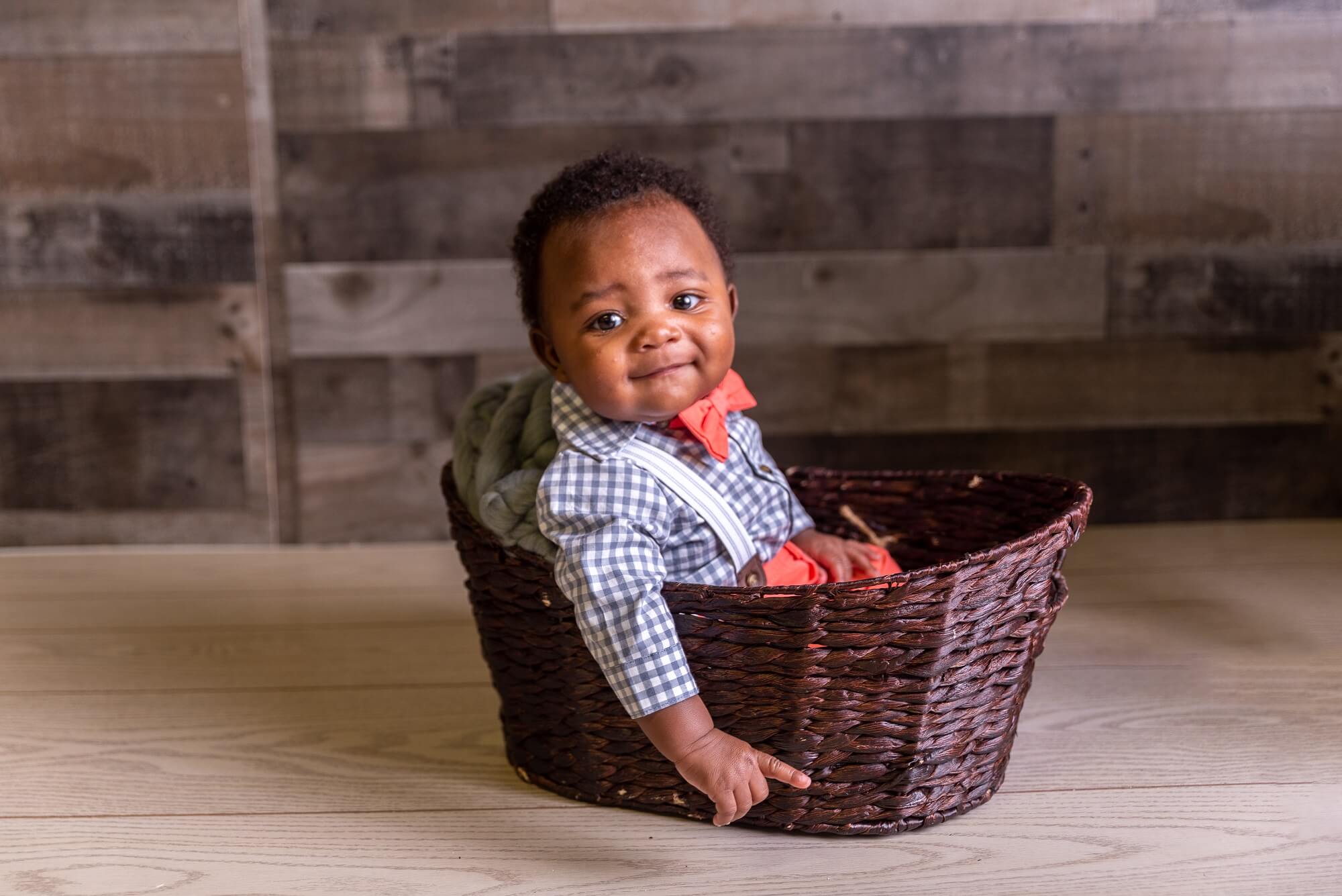 baby sitting in a brown basket smiling at camera for Double Rainbow