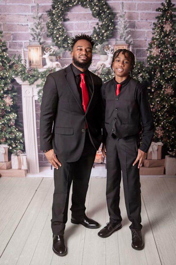 Father and son smiling at camera for holiday session for red and black suits for Pins Mechanical Co. in Cleveland