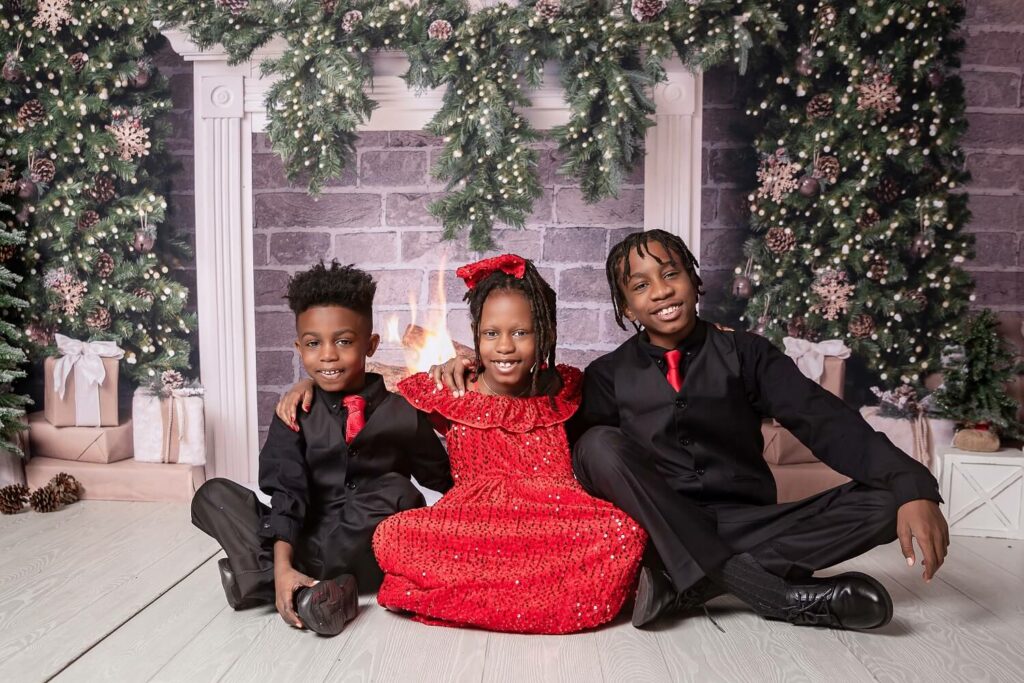 two brother and sisters sitting on floor wearing red and black for a holiday Christmas session Pins Mechanical Co. in Cleveland