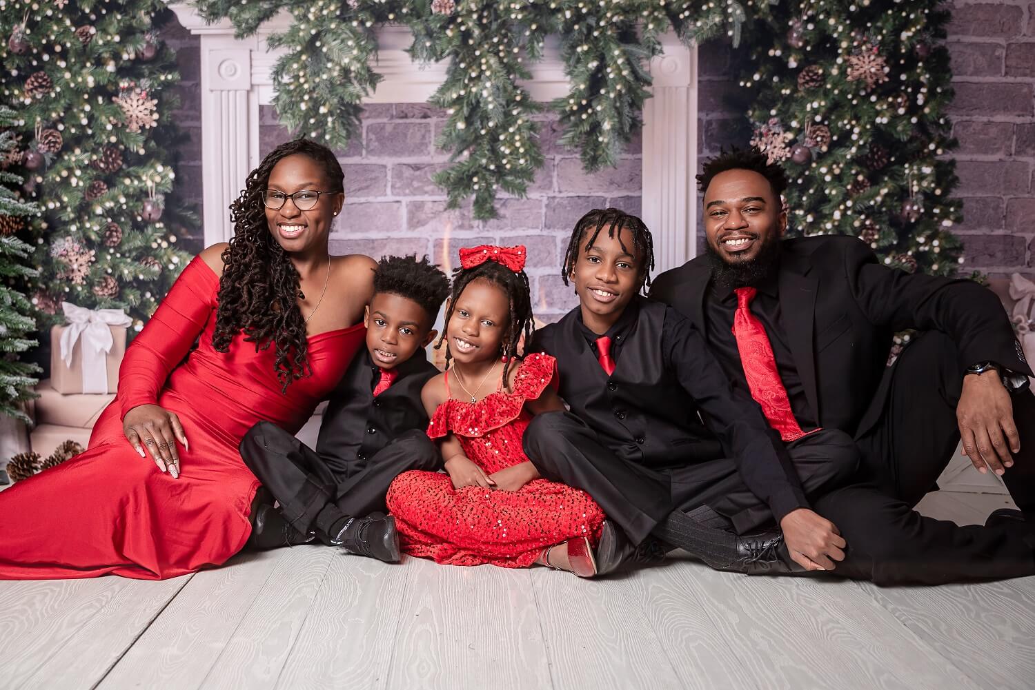 Family sitting on ground in red and black formal wear for Pins Mechanical Co. in Cleveland