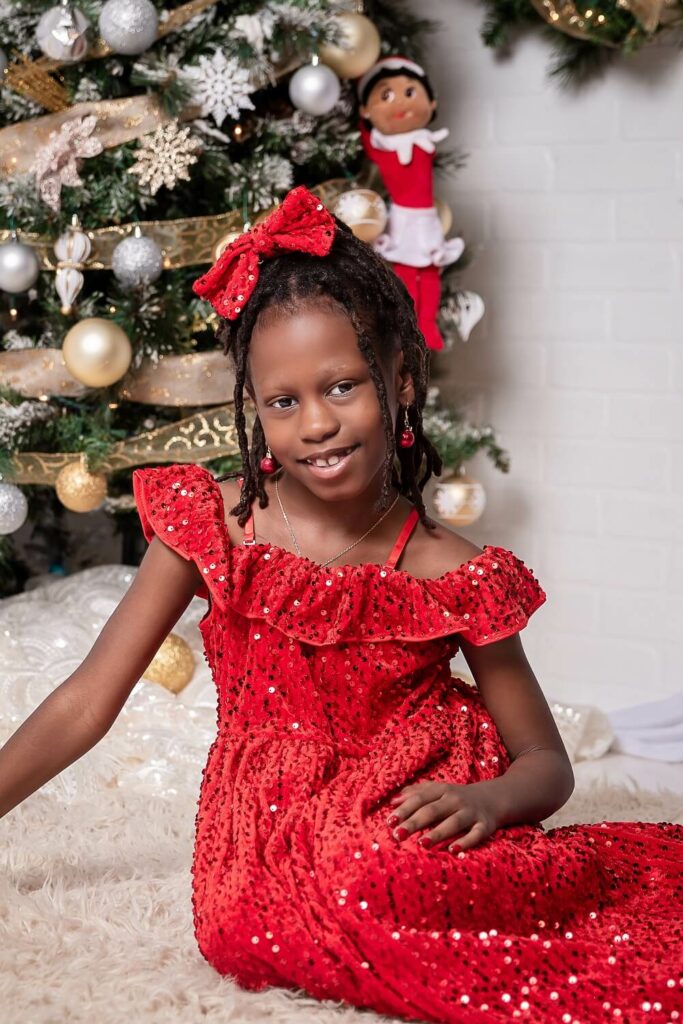 African american girl in red formal dress smiling at camera for Christmas holiday session Pins Mechanical Co. in Cleveland