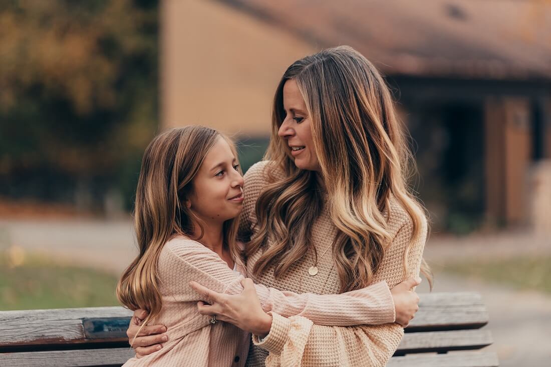 A heartfelt moment between a mother and daughter as they embrace on a park bench, gazing at each other lovingly Fun Activities for 9-11 Year Olds