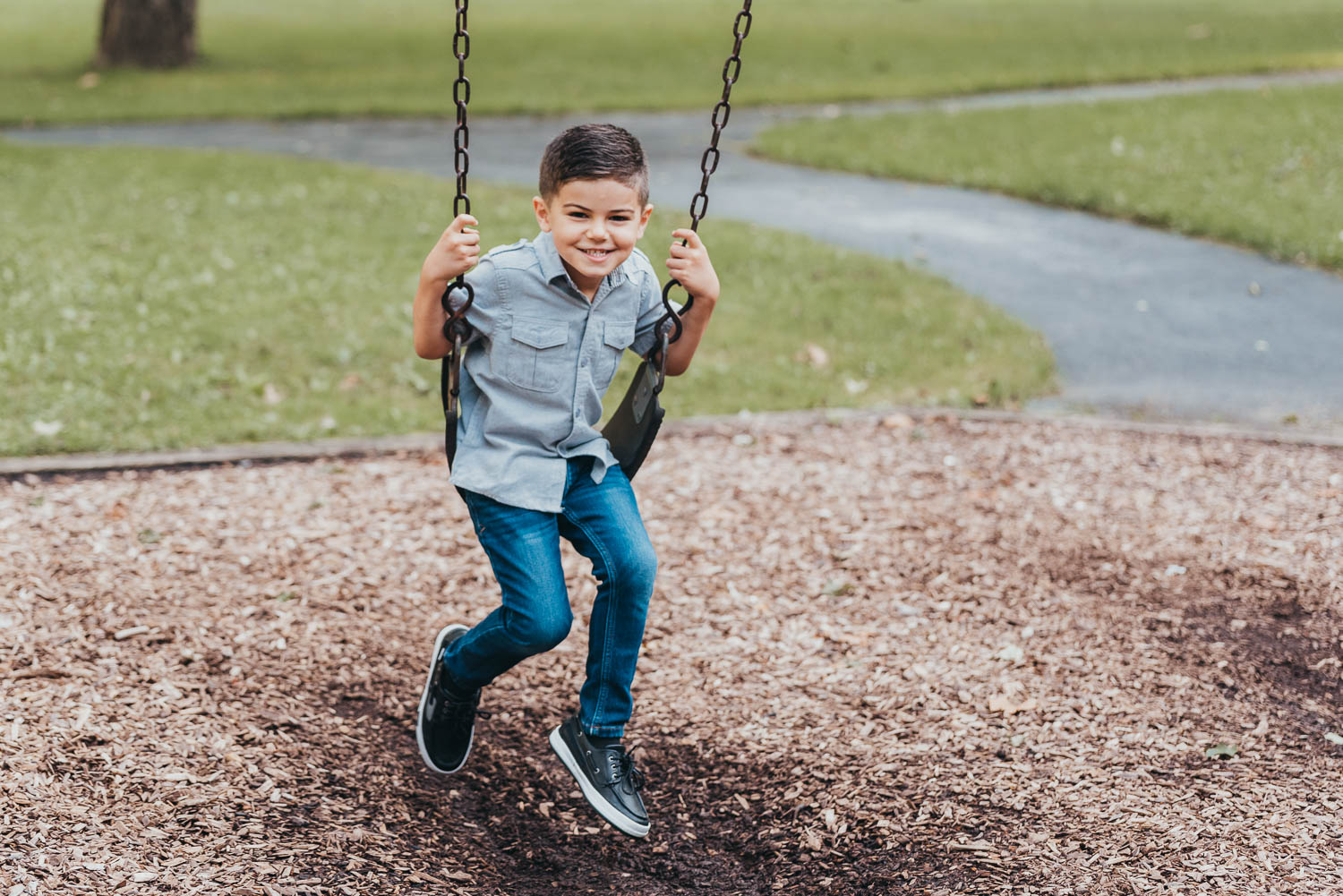 Young boy smiling while swinging at a Northeast Ohio park during a family outing