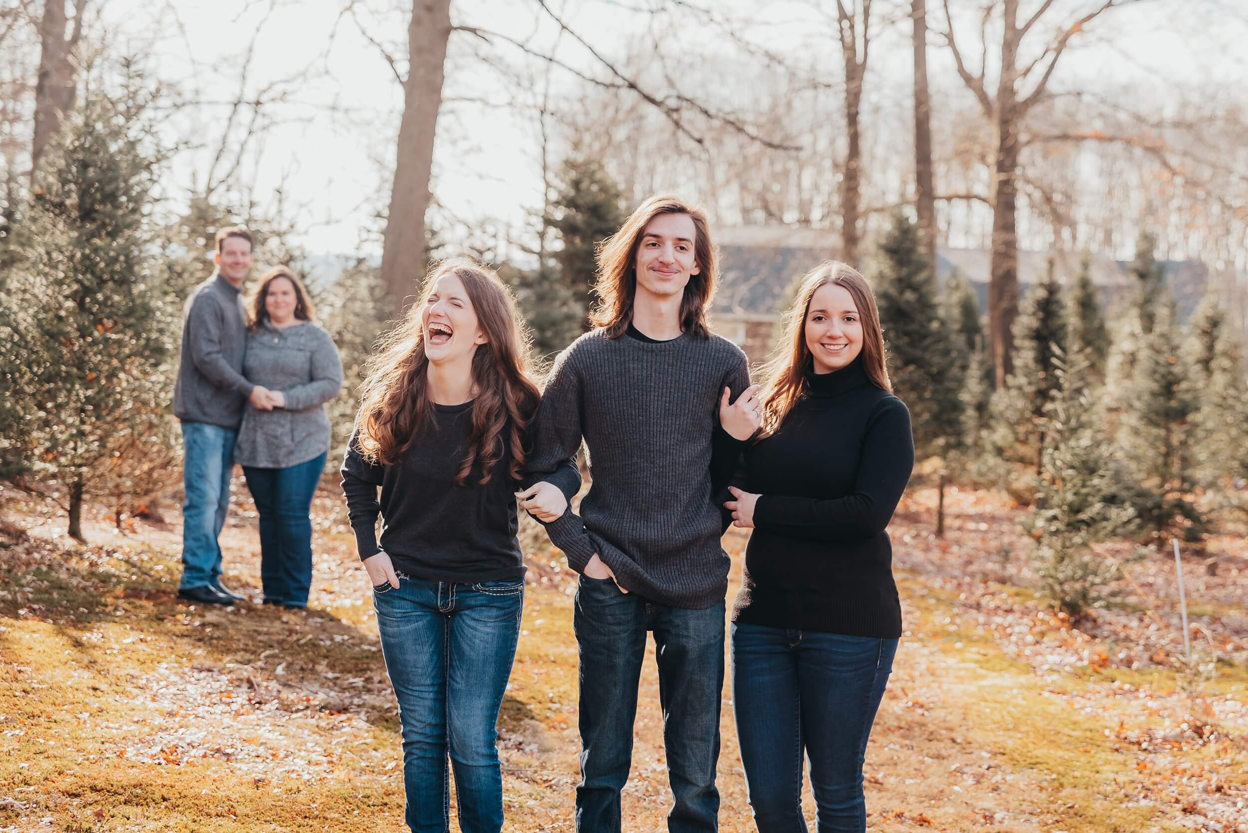 Family laughing together while walking through a Christmas tree farm in Northeast Ohio during the holiday season