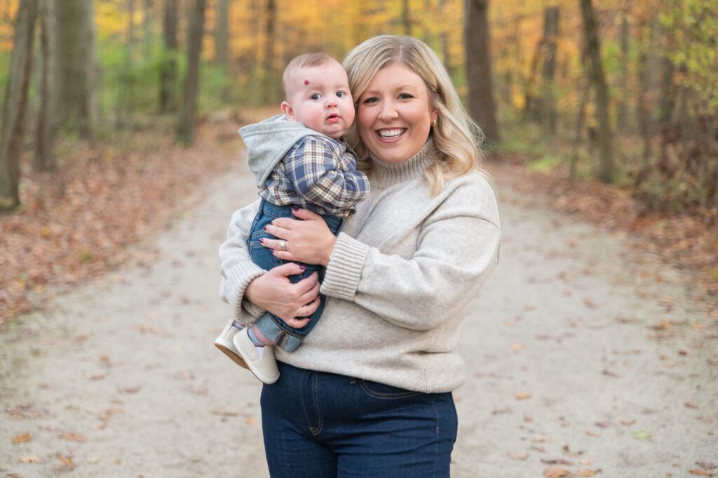 Mom holding her baby in coordinated neutral outfits during fall family photos in Northeast Ohio