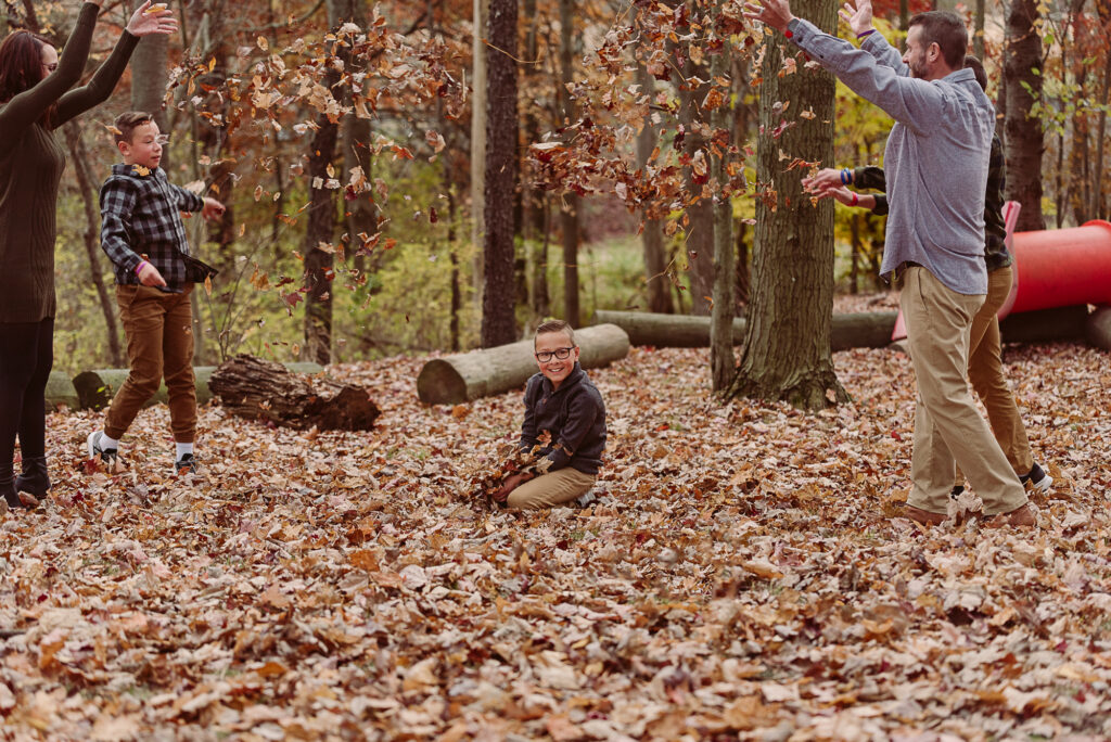 Family playing and tossing autumn leaves during a candid fall family photography session in Northeast Ohio