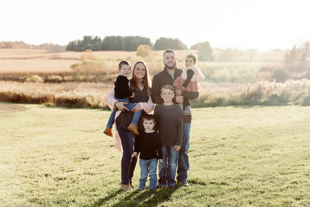 Family of six photographed in a sunlit field during a golden hour family photography session in Northeast Ohio