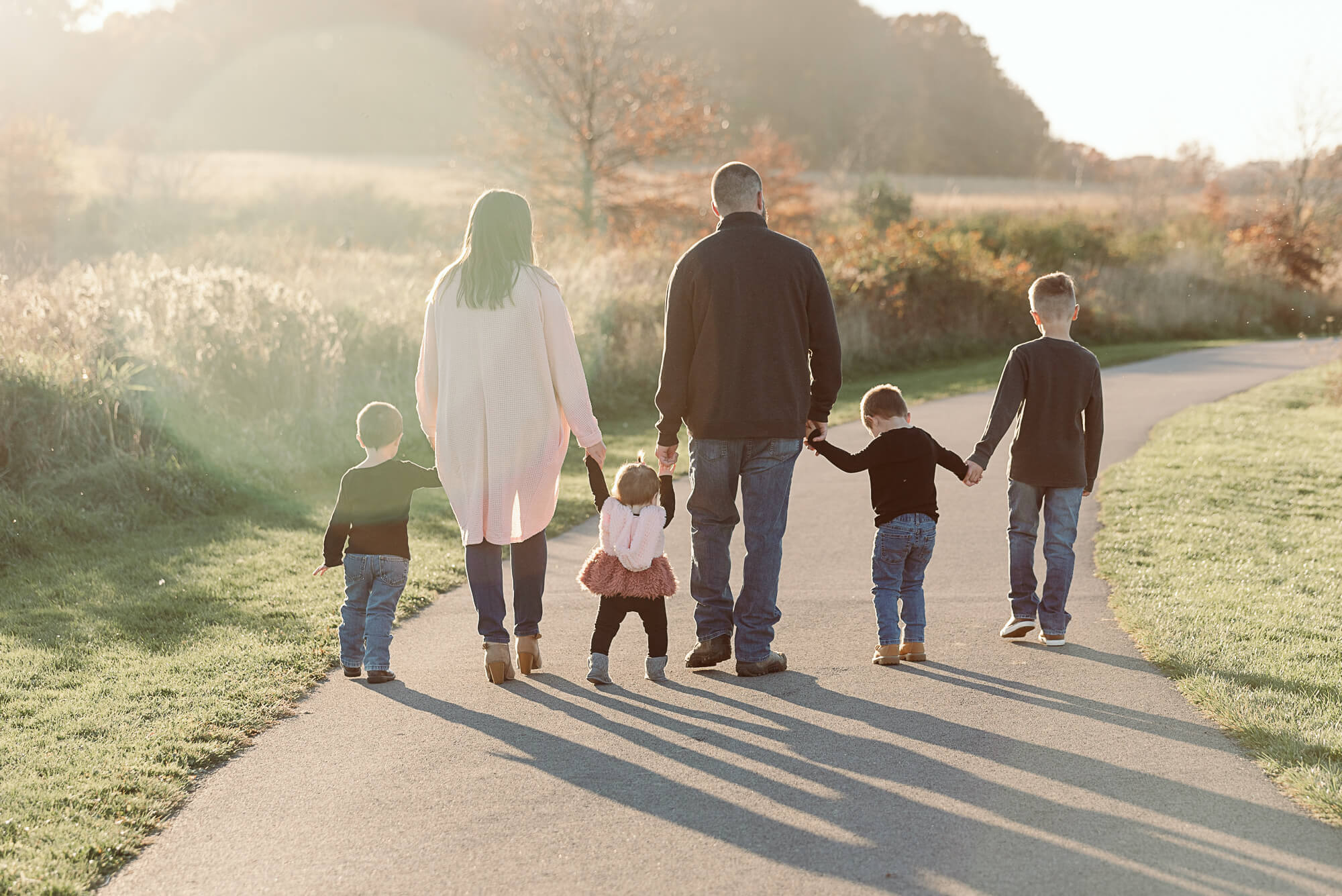 Parents walking hand in hand with their four children during a sunset family photography session in Northeast Ohio