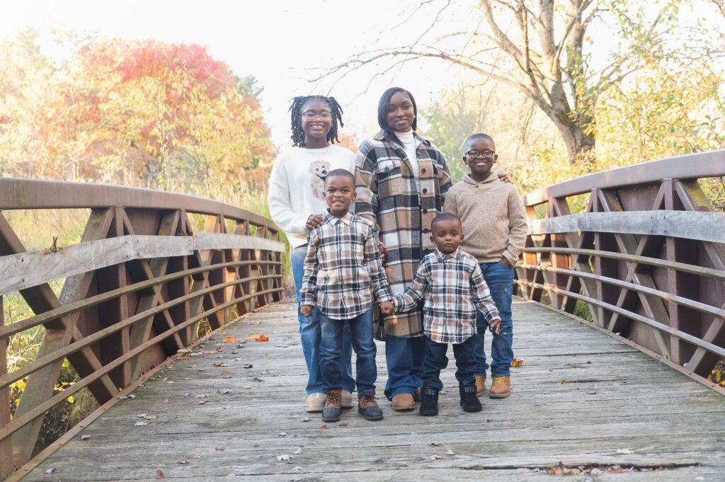 Mother and four children posing together on a wooden bridge surrounded by colorful fall foliage in Northeast Ohio for Family-Friendly Drive-In Movie Theaters in Northeast Ohio
