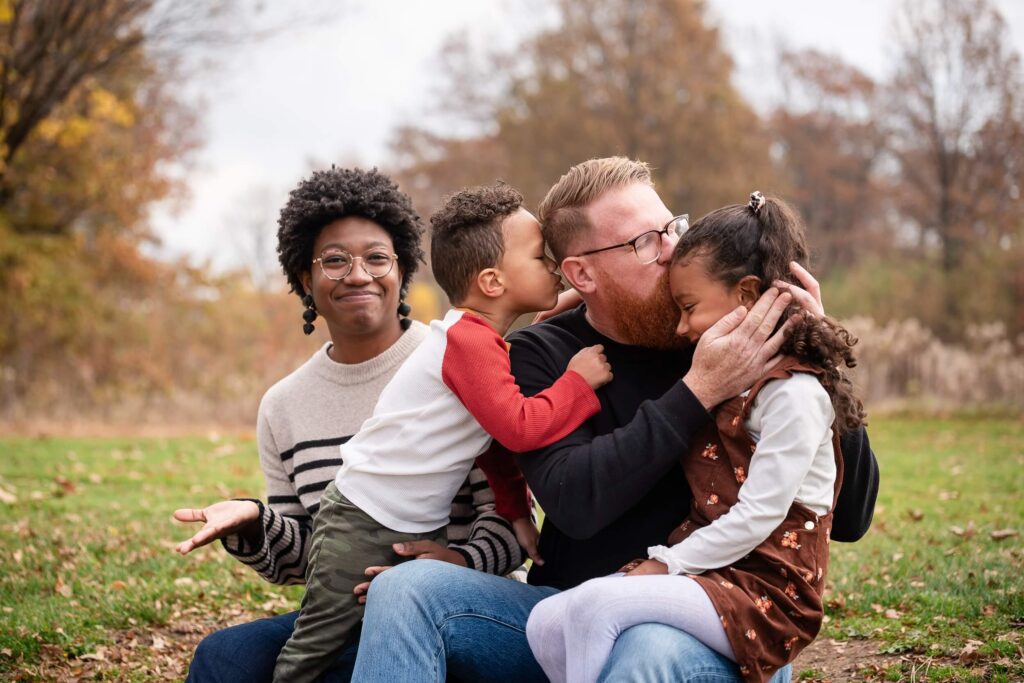 Parents sharing a playful moment with their two children during an outdoor fall family photography session in Northeast Ohio